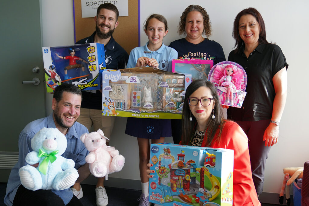 Spectrum staff with staff, student and parent from Cana Catholic Primary School dontating toys for refugee kids as part of their mission work